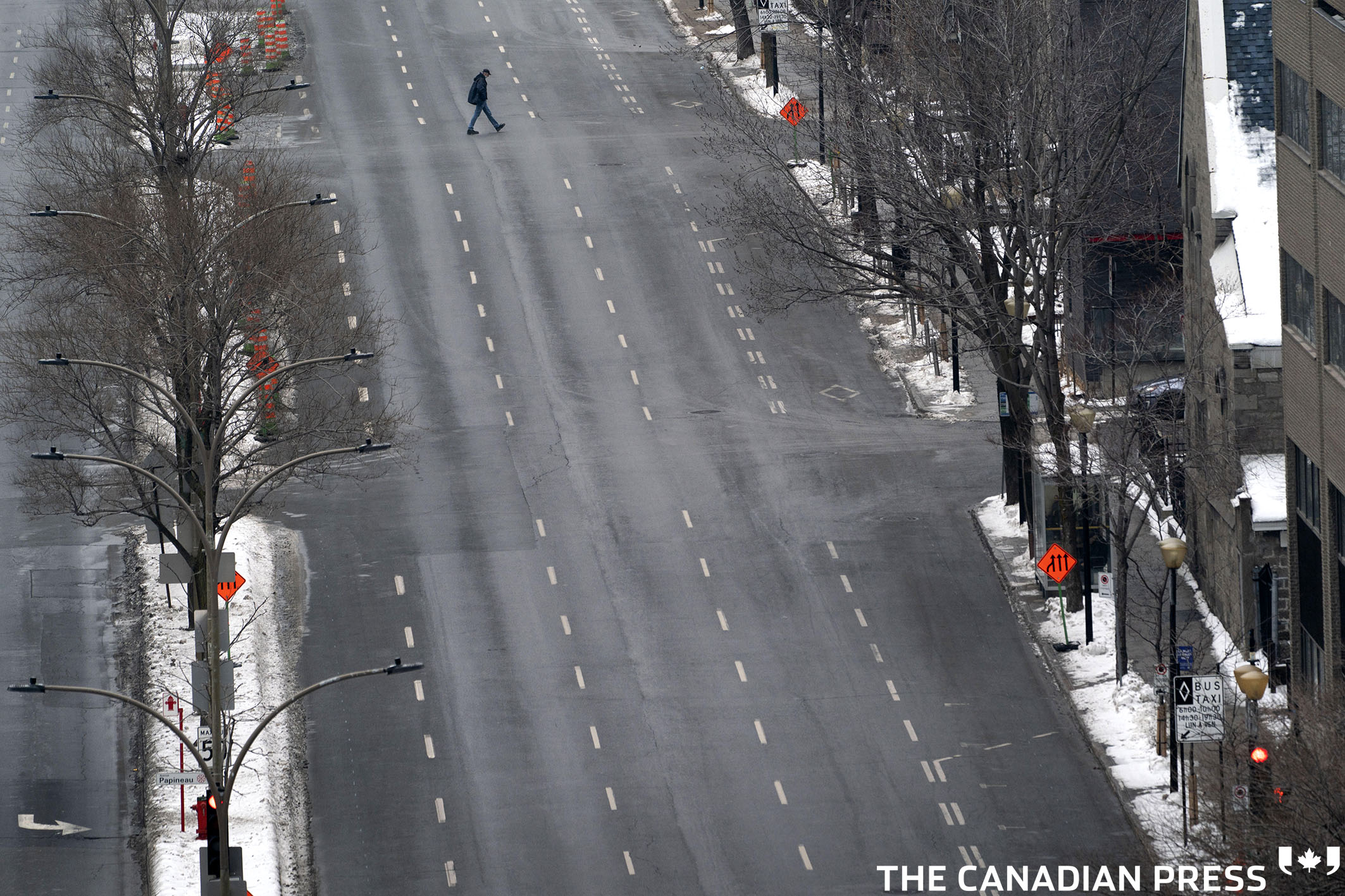 A lone pedestrian crosses an empty Rene-Levesque Boulevard under Quebec's new COVID-19 lockdown in Montreal, on Wednesday, January 13, 2021. THE CANADIAN PRESS/Paul Chiasson
