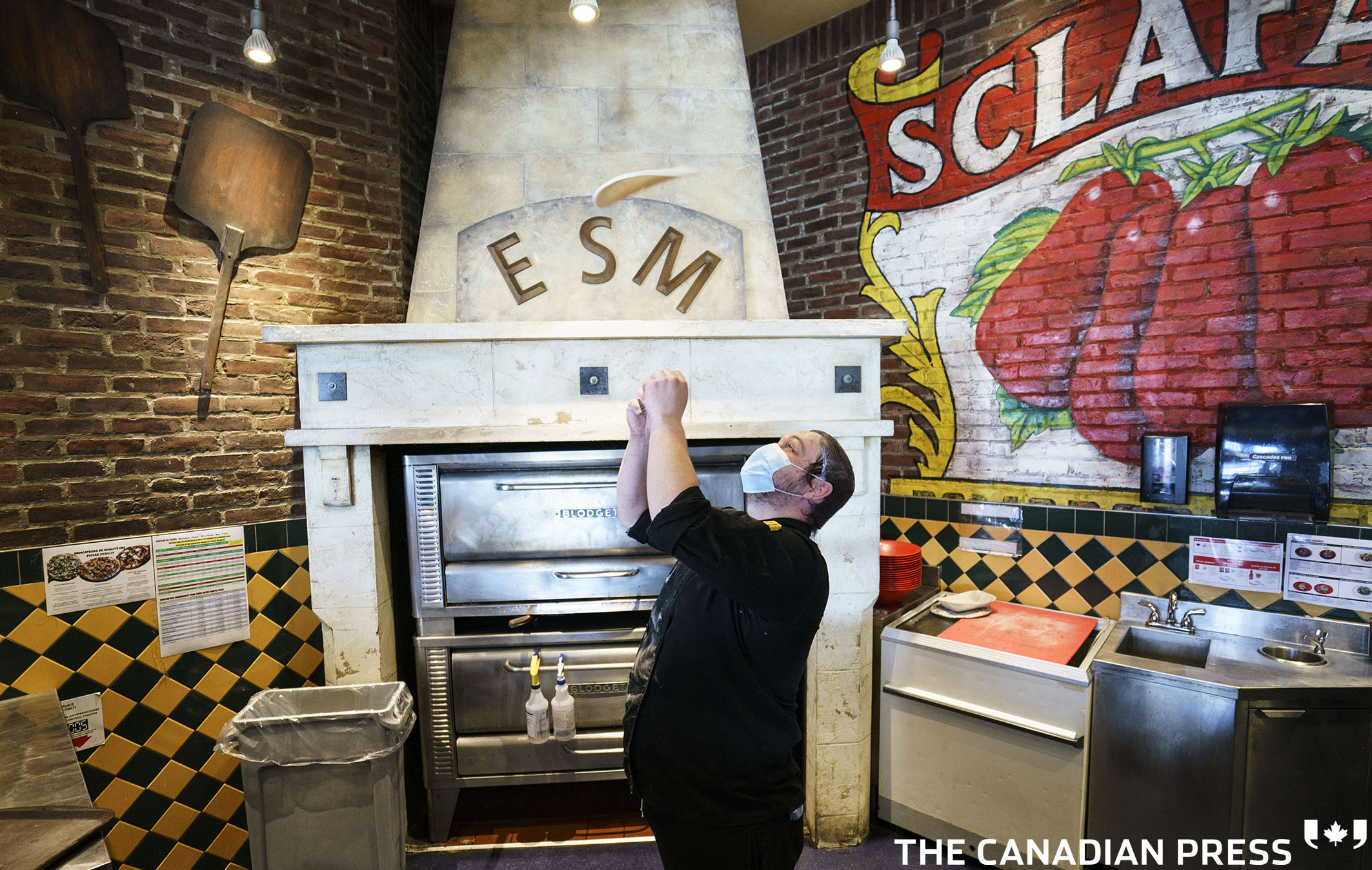 Chef Maxime Roy flips a pizza dough at the Eastside Mario’s restaurant in Bromont, Que. on Monday, March 8, 2021. Customers are allowed to dine in as of Monday in restaurants outside of the greater Montreal. THE CANADIAN PRESS/Paul Chiasson