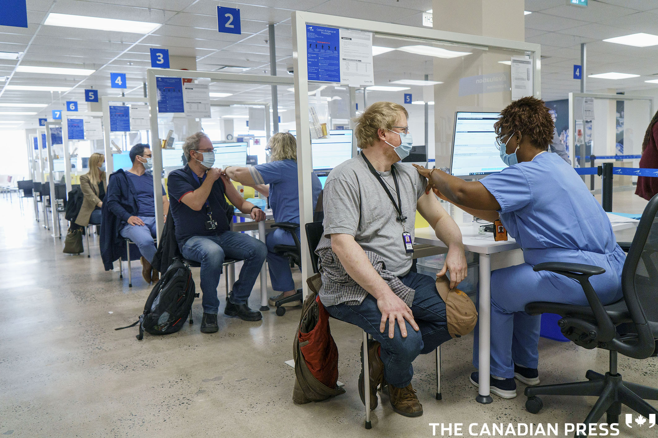Employees are vaccinated at a COVID-19 vaccination clinic at CAE headquarters in Montreal, on Monday, April 26, 2021. A provincial program to provide vaccinations at large businesses began today at the Montreal headquarters of the flight simulation technology manufacturer. THE CANADIAN PRESS/Paul Chiasson