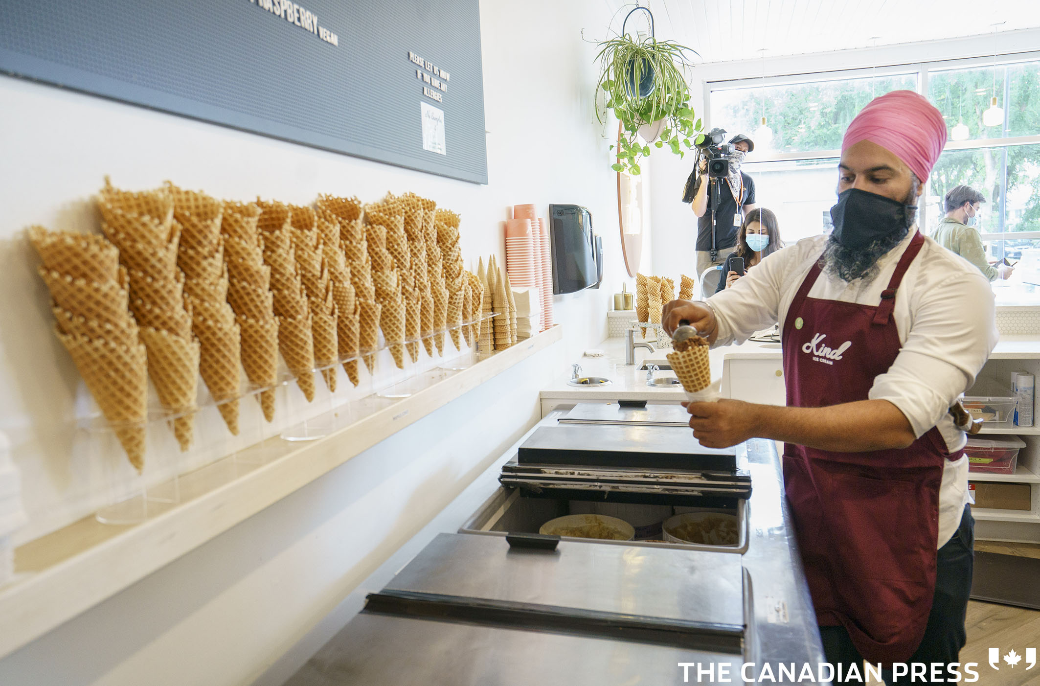 NDP leader Jagmeet Singh prepares an ice cream cone during a campaign stop at an ice cream shop in Edmonton, on Thursday, August 19, 2021. THE CANADIAN PRESS/Paul Chiasson