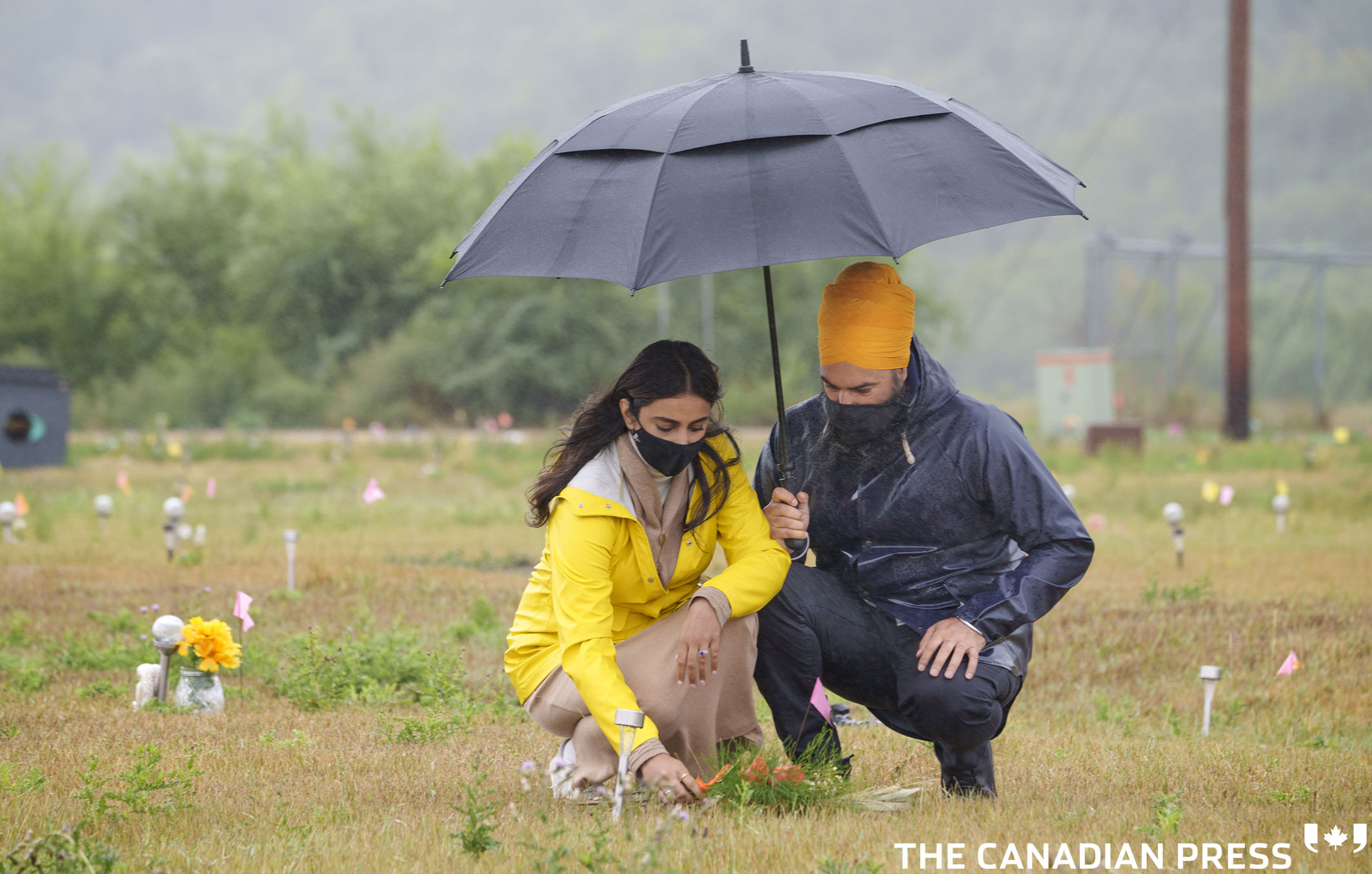 NDP leader Jagmeet Singh and his wife Gurkiran Kaur Sidhu place flowers on a grave where 751 bodies were buried on the grounds of the Marieval Indian Residential School in Cowessness First Nation, Sask., on Friday, August 20, 2021. THE CANADIAN PRESS/Paul Chiasson