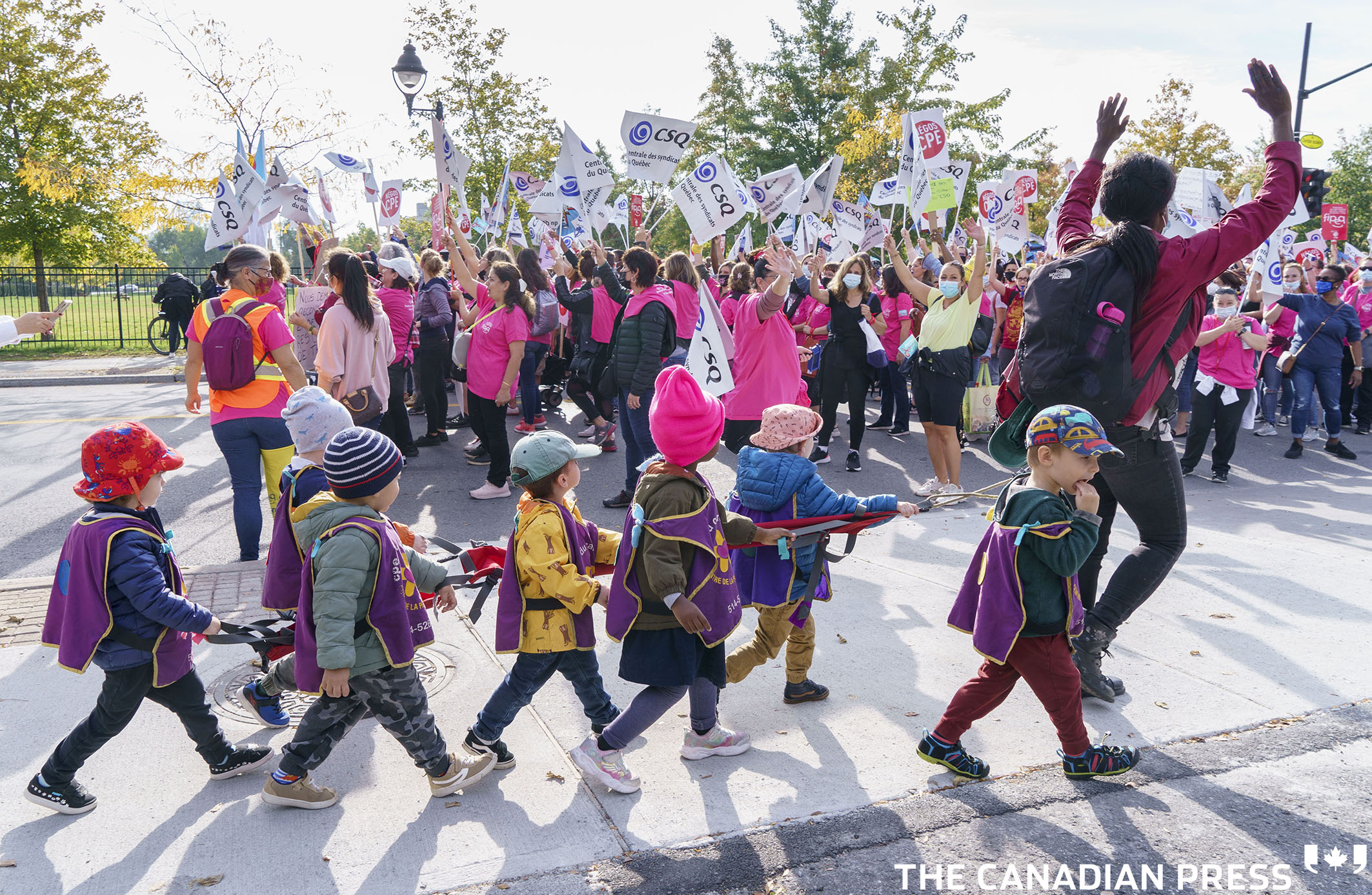 Children from a daycare walk past a demonstration of daycare workers on the first day of rotating strikes in Montreal on Tuesday, October 12, 2021. THE CANADIAN PRESS/Paul Chiasson