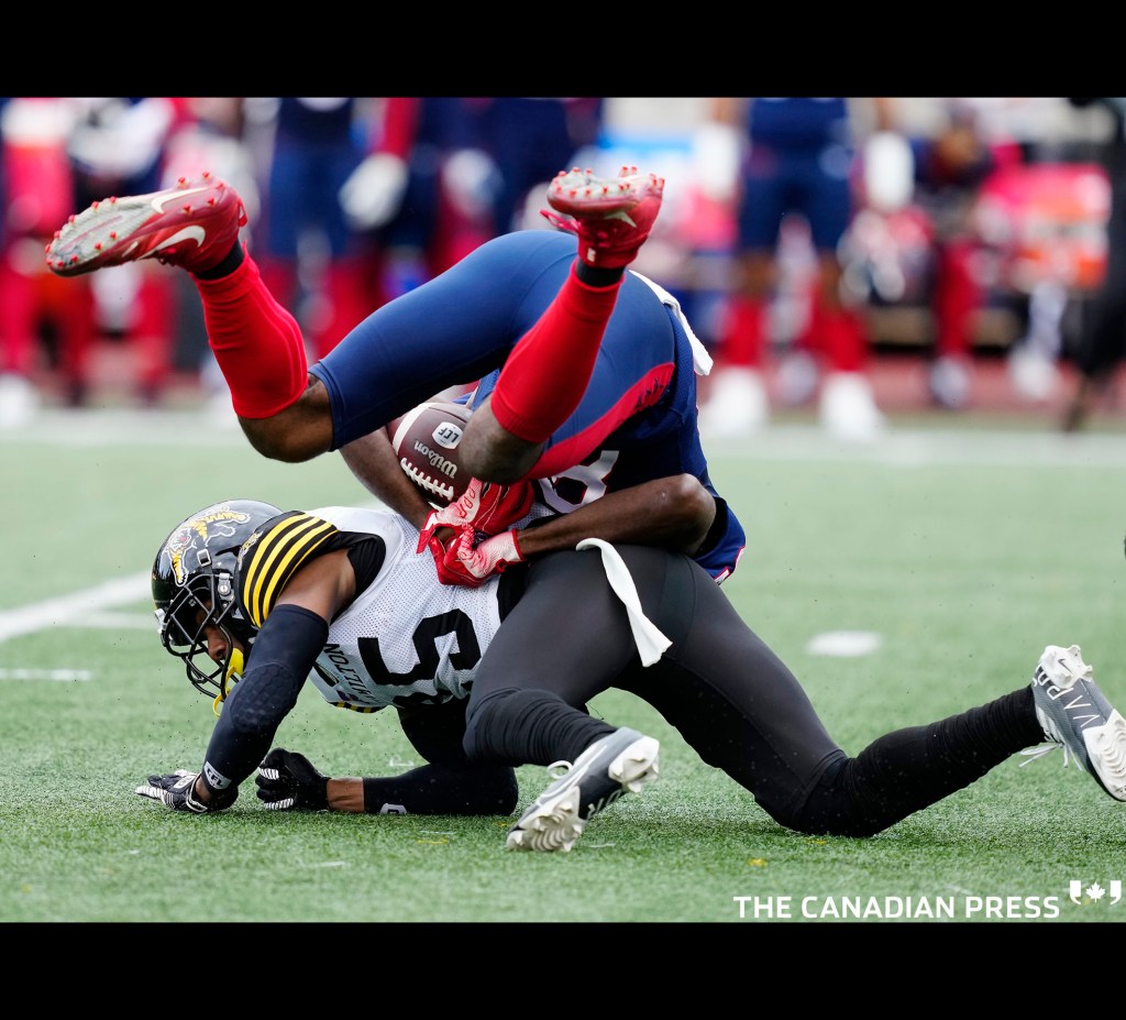 Montreal Alouettes wide receiver Eugene Lewis is upended by Hamilton Tiger-Cats defensive back Jumal Rolle (25) during first quarter CFL Eastern semi-final football action on Sunday, November 6, 2022 in Montreal. THE CANADIAN PRESS/Paul Chiasson